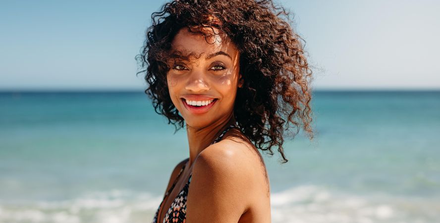 Side view of a smiling woman standing at the beach