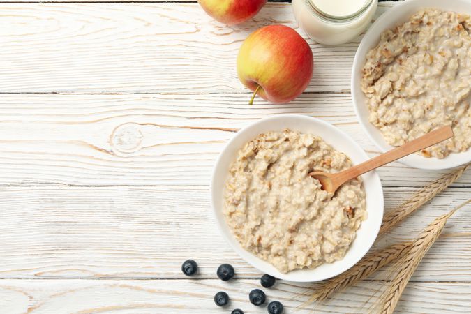 Composition with oatmeal porridge on blank wooden background. Cooking breakfast