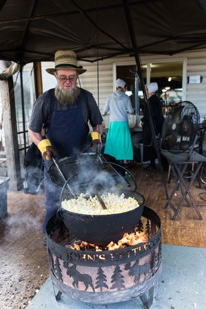 An Amishman tends to popcorn, prepared over an open fire, Berlin, Ohio