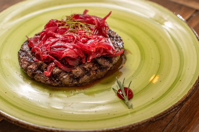 Gourmet beef burger with caramelized red onions on a rustic plate