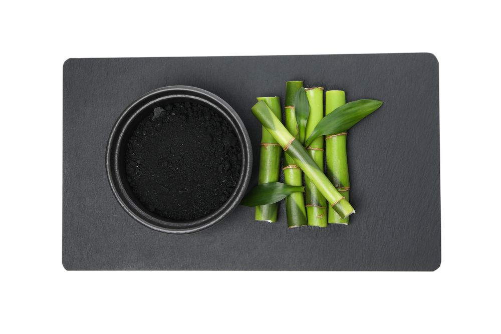 Fresh bamboo shoots with charcoal in a bowl, isolated on plain background