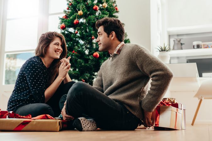Smiling couple exchanging Christmas presents in their living room