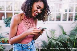Happy young woman smiling while texting on a smartphone surrounded by plants v4mRzb