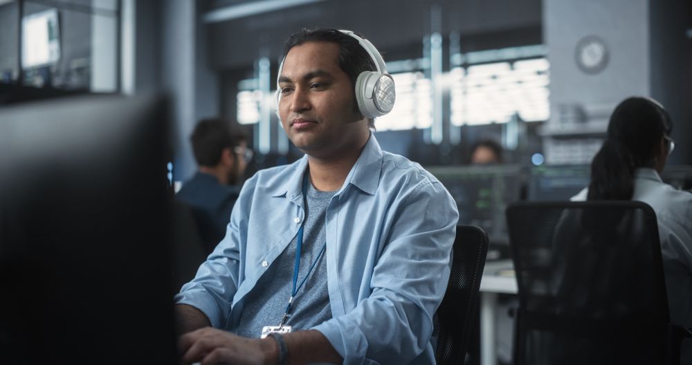 Indian System Administrator Working in a Research E-Business Facility on a Desktop Computer.
