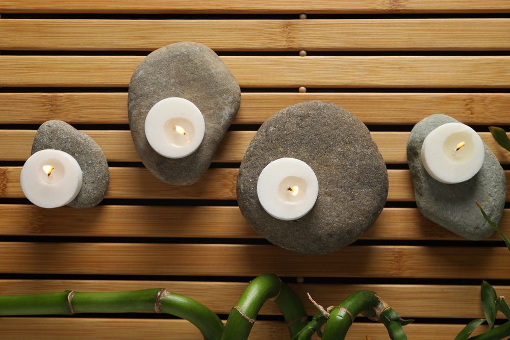 Stones, candles and bamboo on wooden background, top view
