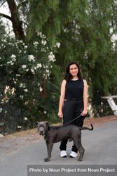 Full length shot of woman in casual athletic attire standing with her dog on the street bGRav4