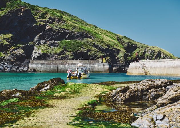 Commercial fishing boat parked by cliffs in shallow water