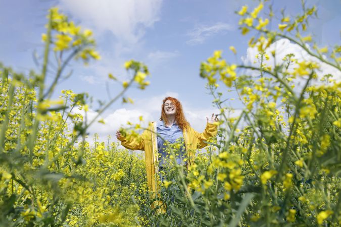Happy red haired woman smiling in a rapeseed field