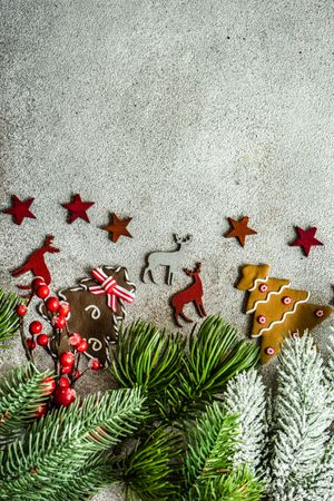 Christmas card concept of gingerbread cookies and pine on concrete
