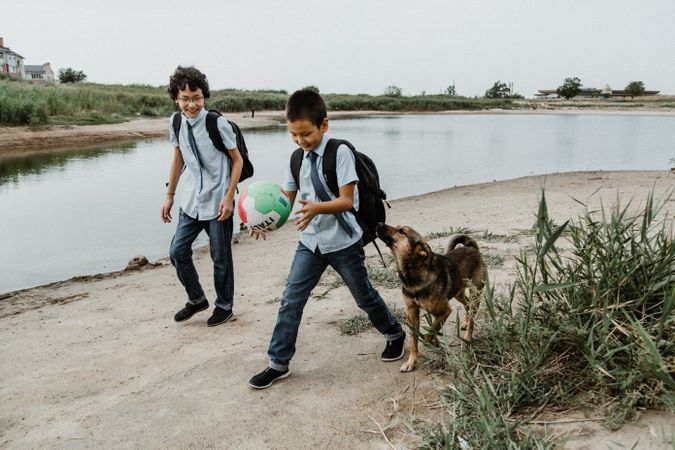 Cute boys with ball and dog near river