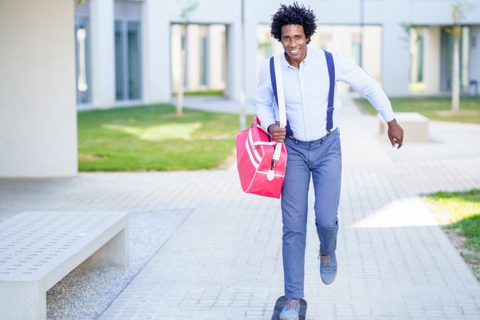 Smiling man with sports bag roller skating out of office