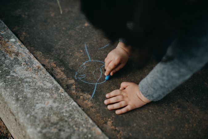 Child drawing with chalk outside