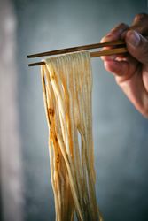 Crop person with noodles on food sticks