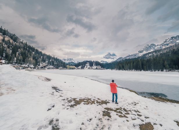 Unrecognizable person standing in snow surrounded by forest and mountains