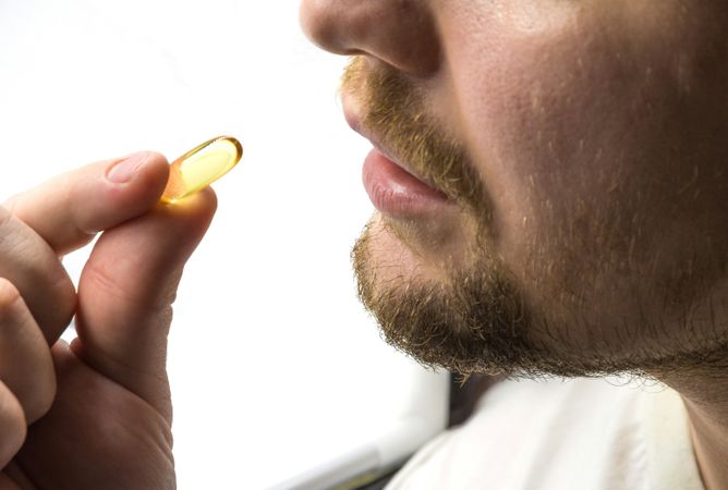 Man Taking Single Vitamin or Supplement Capsule