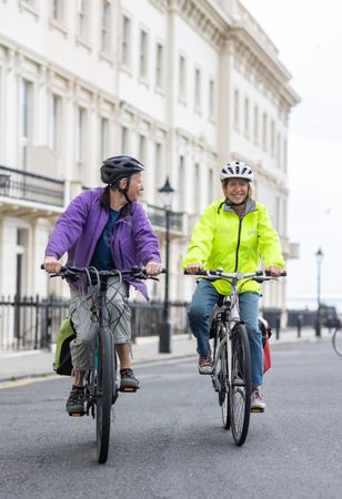 Two older people riding bikes through town