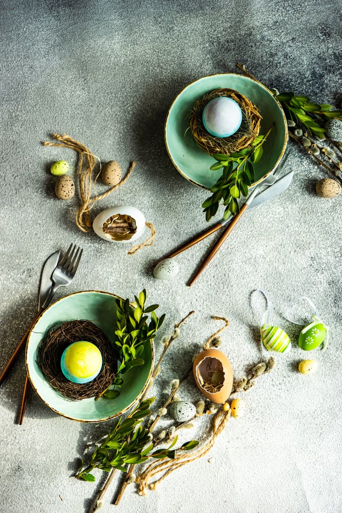 Top view of Easter table setting with pastel bowl with decorative egg in nest