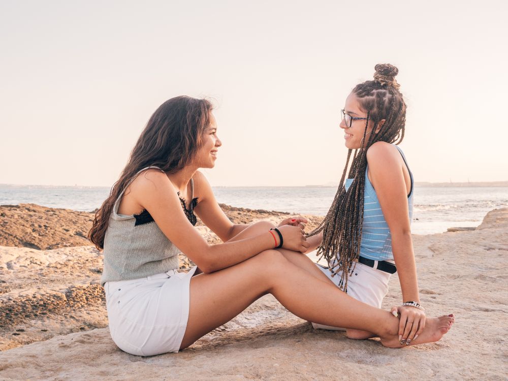 Smiling trendy young women relaxing on seashore