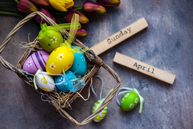 Basket of colorful Easter egg decorations on grey table
