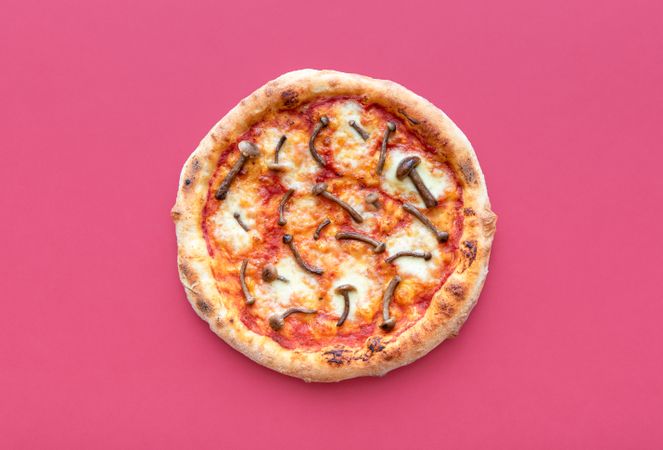 Homemade pizza on a magenta background, top view