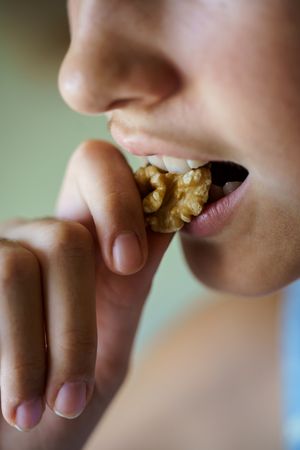 Mouth of girl biting into walnut