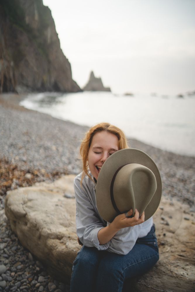 Woman resting on beach stone by sea