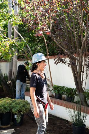 Female contractor working in garden with male colleague in the background