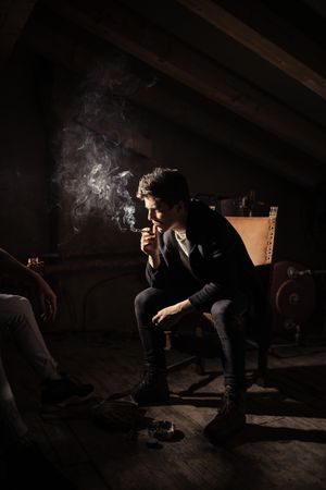 Men with guitar, cigarette and smartphone sitting on chairs