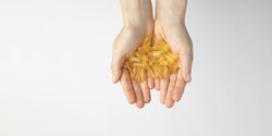 The hands of a woman hold a lot of oil capsules with omega 3, food supplement