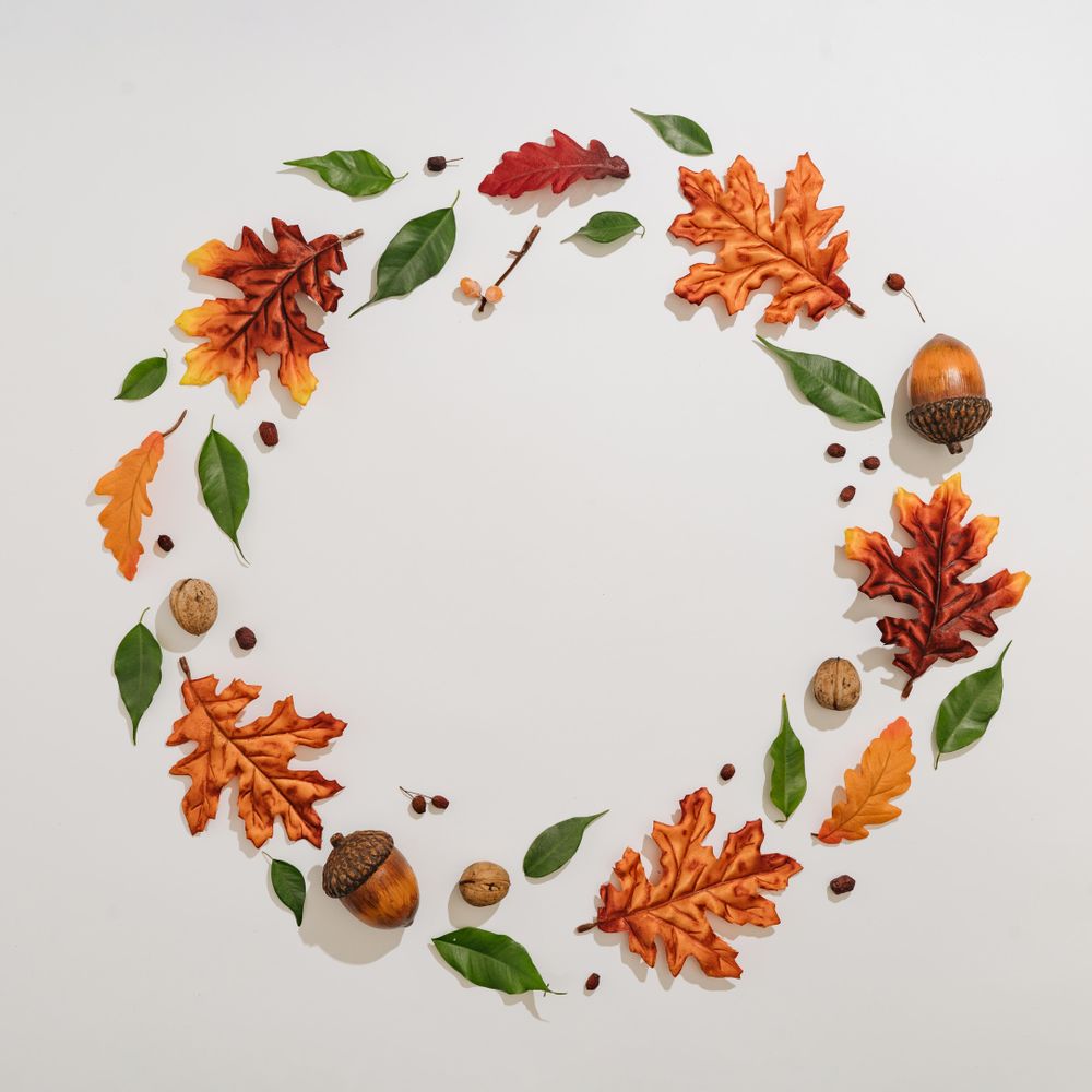 Autumn branches and leaves arranged in festive wreath on light background