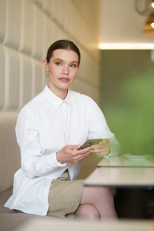Businesswoman using phone sitting in a cafeteria
