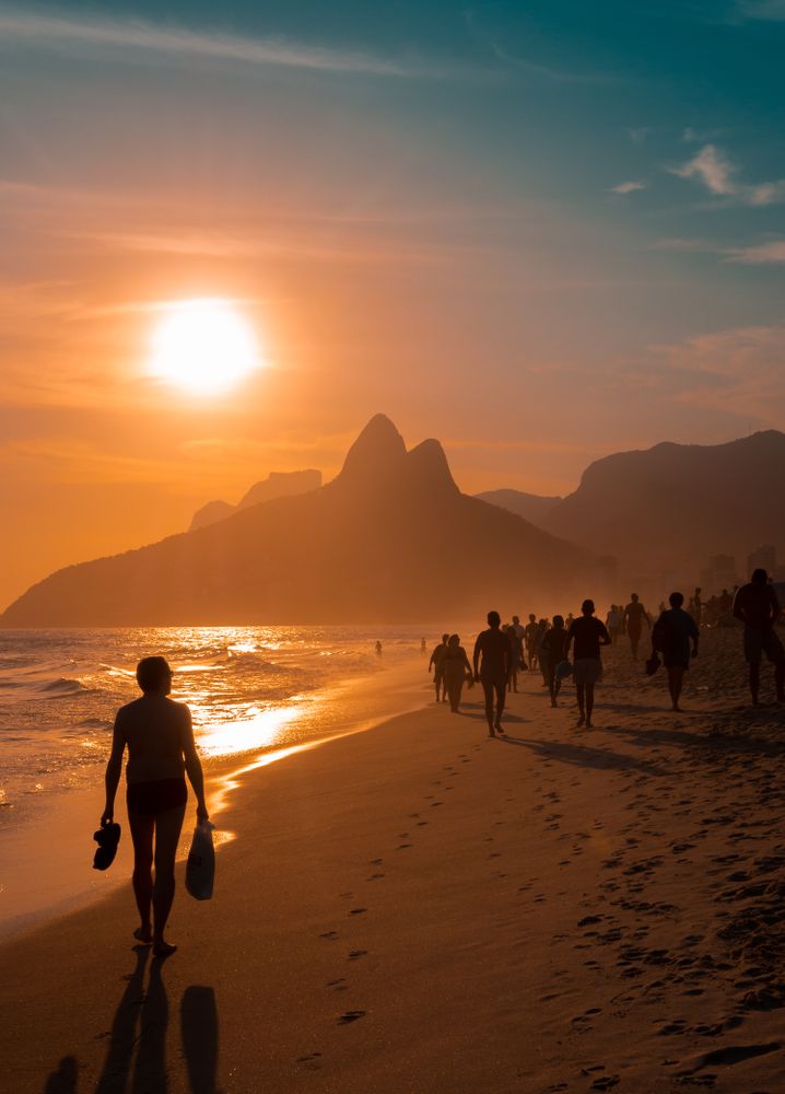 Rio de Janeiro, Brazil - February, 12 2014: Group of anonymous people walking on sandy Ipanema Beach near waving sea during wonderful sundown