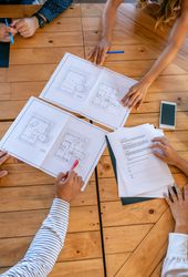 Unrecognizable architects in a work meeting looking at building plans of a house