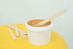 Liquid yellow paste for sugaring on yellow background, space for text