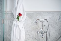Interior of luxury bathroom with terry bathrobe with red rose