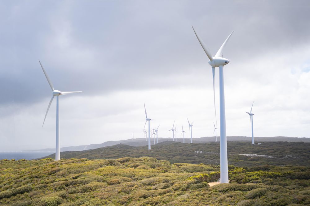 Wind turbines on green grass field under cloudy sky