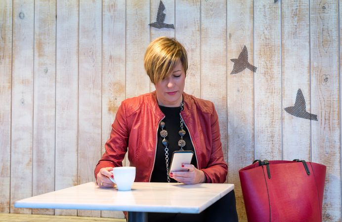 Woman in red checking phone in cafe