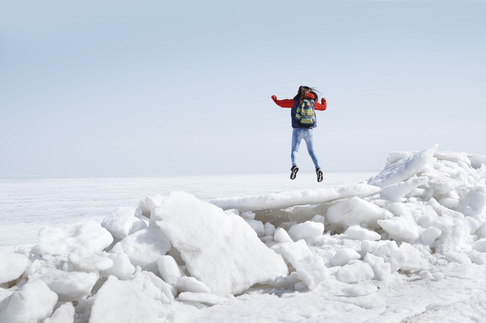 Young adult woman outdoors travelling with backpack in icy lands