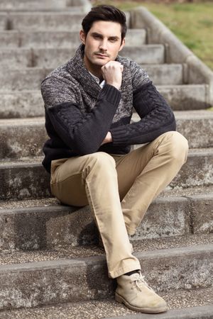 Man sitting in warm sweater coat on steps outside