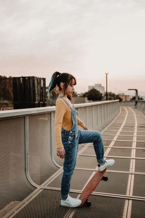 Girl with skateboard on walkway