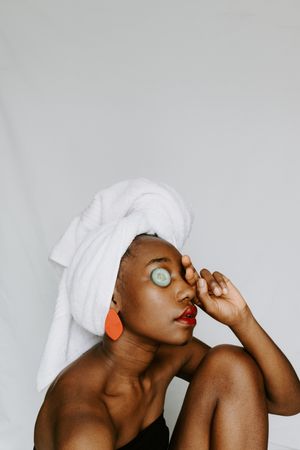 Woman with towel around her head and cucumber on face