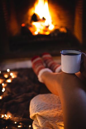 Crop legs and mug near fireplace