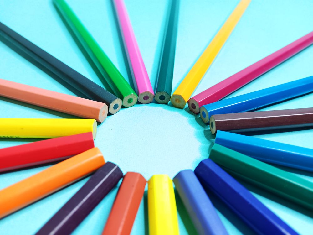 light blue background with a circular arrangement of colored pencils