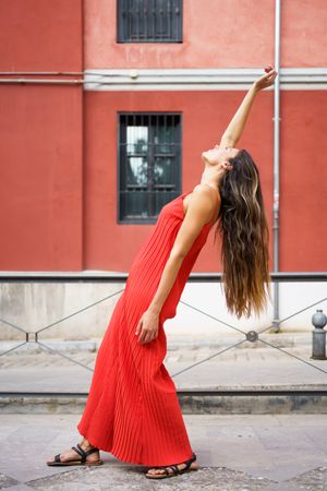 An Elegant Woman in a Beautiful Red Dress Posing Gracefully Outdoors in a Scenic Setting