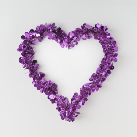 Purple confetti shaped in heart outline on light background