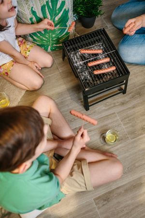 Top view of unrecognizable family grilling and eating sausages on barbecue