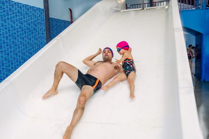 Father and daughter sliding in water park