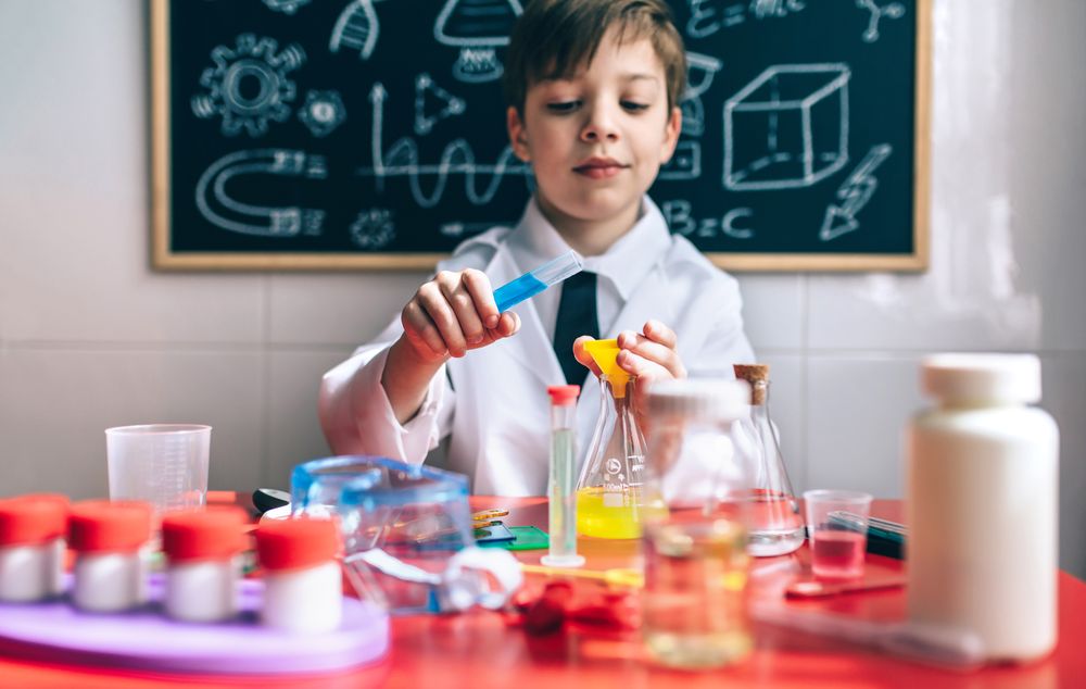 Serious little boy playing with chemical liquids
