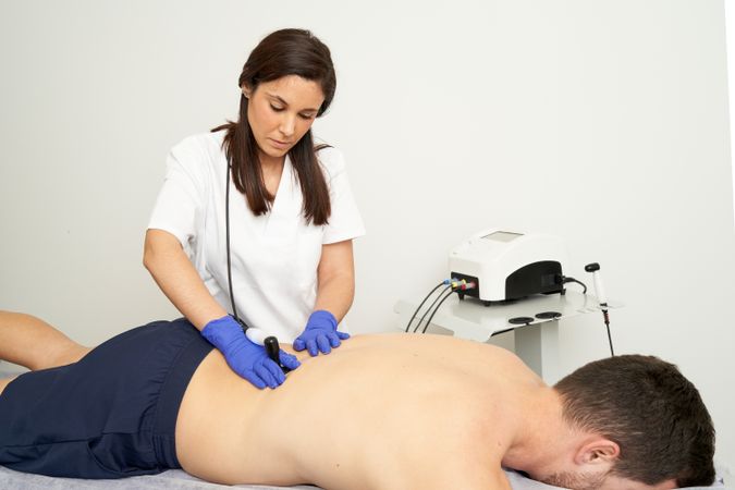 A female physiotherapist giving diathermy treatment on the patie