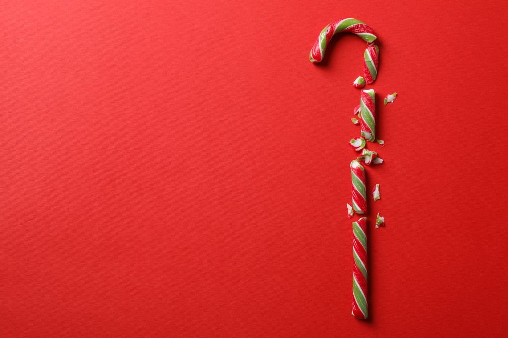 Broken candy cane on red background, space for text